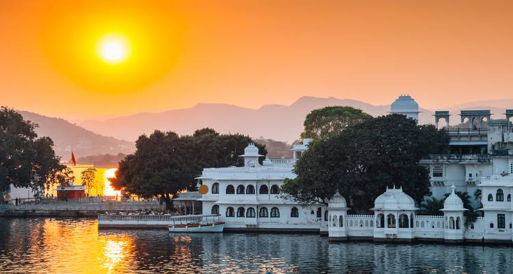 Coucher de soleil sur un lac avec une architecture blanche traditionnelle.
