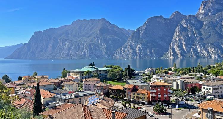 Picturesque town of Riva del Garda on the edge of Lake Garda, framed by towering limestone mountains.