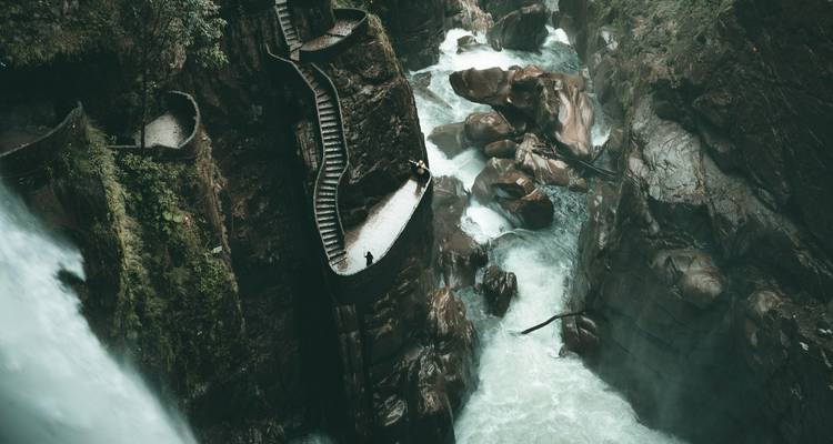 Cascade tombant dans une gorge rocheuse avec un escalier qui serpente vers le haut.