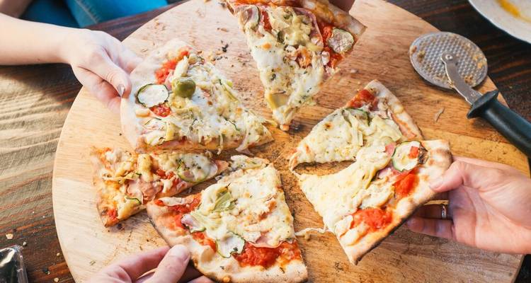 Des tranches de pizza avec des garnitures sur une planche en bois.