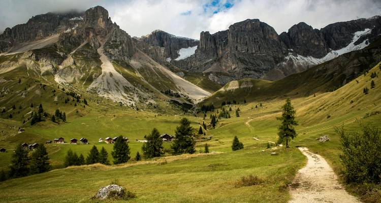 Mountain valley with scattered cabins and a winding path.