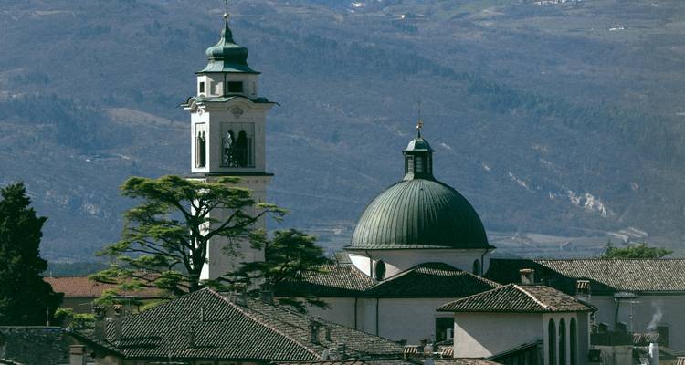 Historic church with a green dome amidst mountainous backdrop.