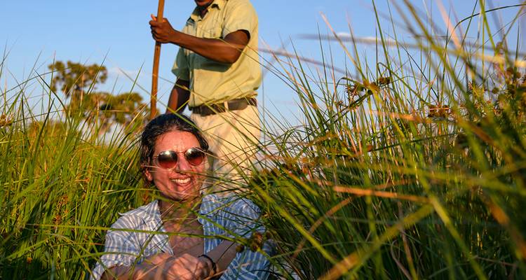 People navigating through tall grass in a canoe.