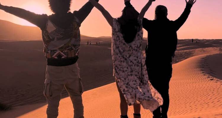 Personas celebrando el atardecer en el desierto.