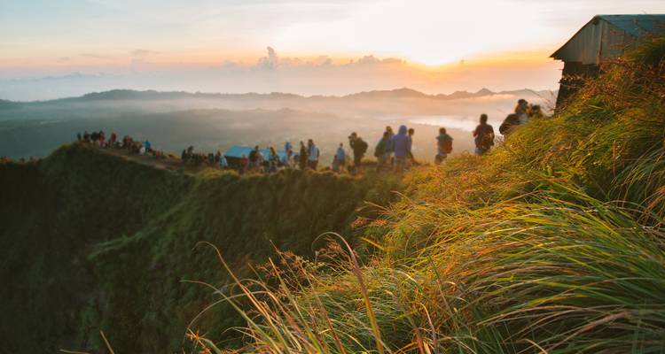 Hikers on a mountain ridge at sunrise with scenic views.