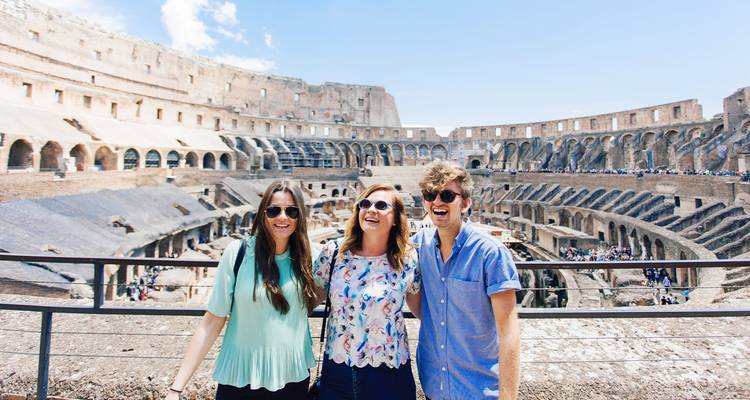 Drie vrienden glimlachen voor een foto in het iconische Colosseum-amfitheater van Rome.