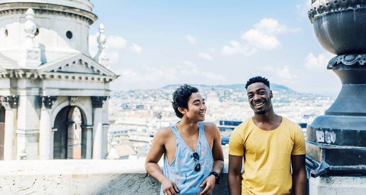 Two friends posing happily with a city view in the background.