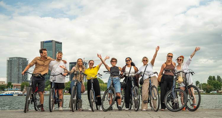 Groupe de personnes avec des vélos profitant d'une vue sur la ville au bord de l'eau.