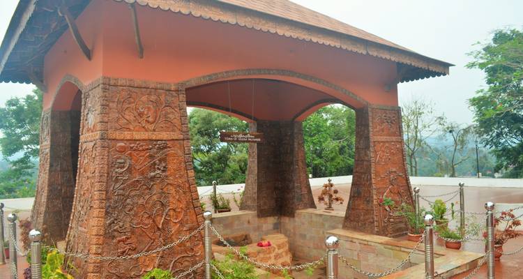 Arceau décoratif avec des sculptures complexes, situé dans un espace jardin.