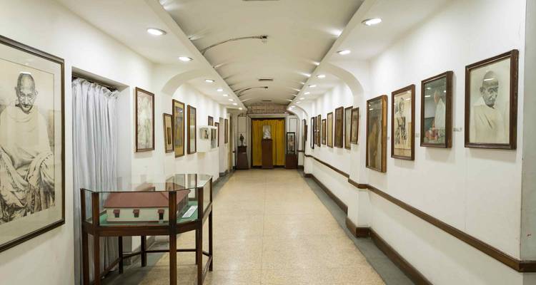 Un couloir dans un musée avec des photographies et des peintures qui bordent les murs.