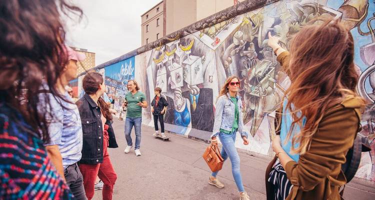 Des gens marchant le long d'un mur avec de l'art de rue coloré.