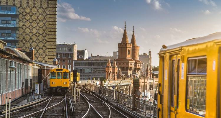 Trains jaunes sur voies surélevées avec bâtiments de ville et tours.