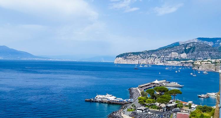 Vue en bord de mer avec bateaux et collines, similaire à la précédente.