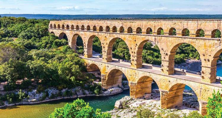 Pont-aqueduc historique au-dessus d'une rivière dans un paysage luxuriant.