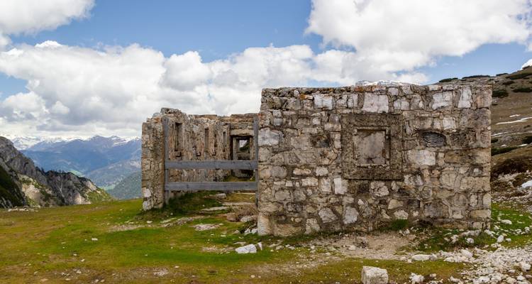 Ruines d'un bâtiment en pierre sur fond de montagnes.