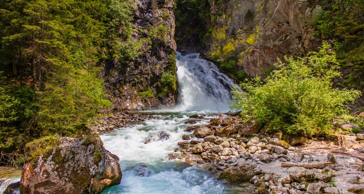 Cascade impétueuse dans un paysage rocheux avec de la verdure.