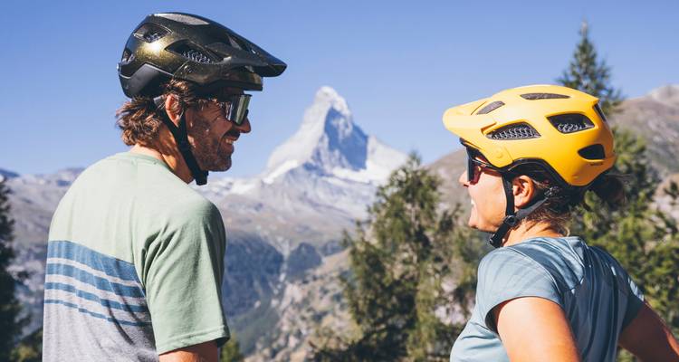 Deux personnes avec des casques admirant le paysage de montagne.