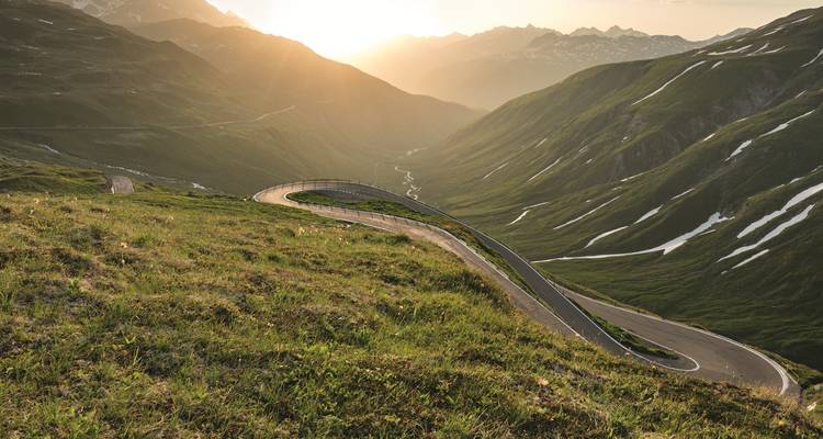 Une route sinueuse à travers une vallée avec une vue époustouflante sur le coucher de soleil.