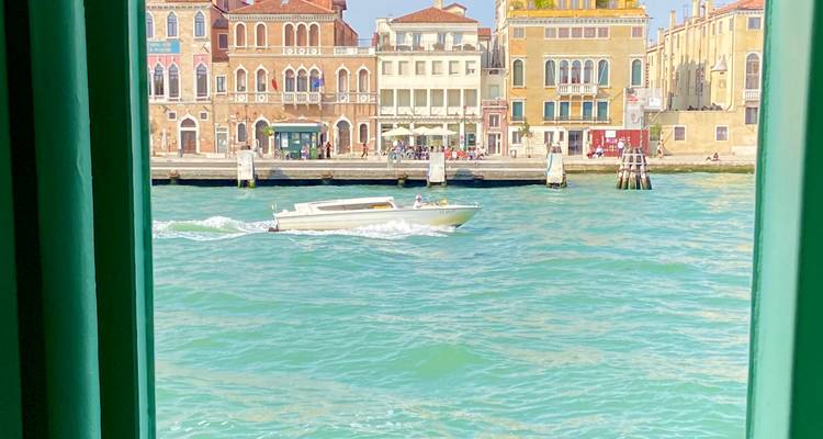 Bateau naviguant sur le canal avec des bâtiments vénitiens colorés en arrière-plan.