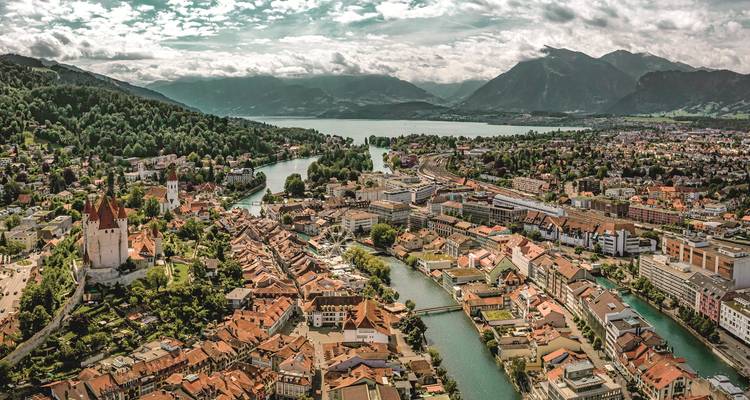 Vue aérienne d'une ville avec une rivière et des montagnes environnantes.