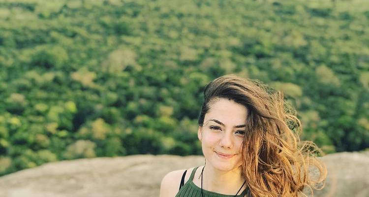 Portrait d'une personne debout sur un rocher avec une forêt en arrière-plan.