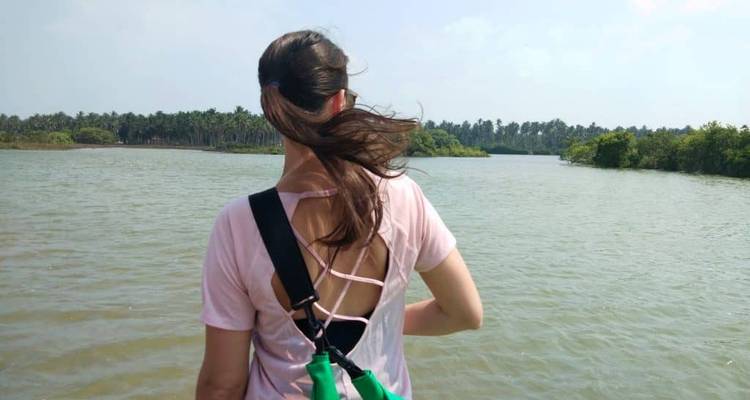 Personne debout avec une vue sur une rivière ou un lac et des palmiers.