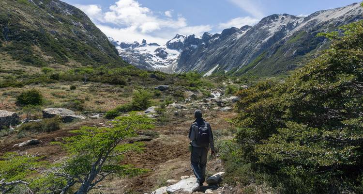 Randonneur dans un paysage montagneux avec des sommets enneigés.