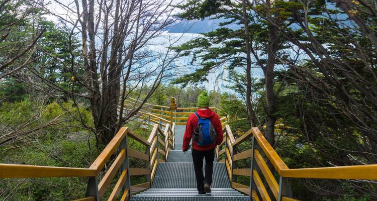 Randonneur descendant les escaliers vers un glacier.