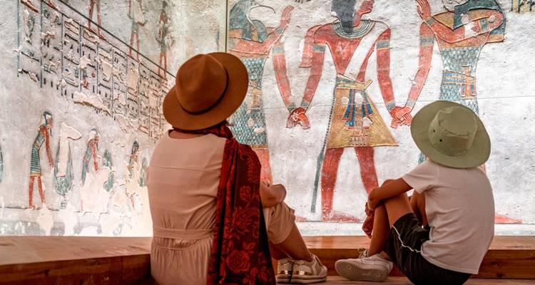 Dos personas viendo frescos de estilo egipcio antiguo.