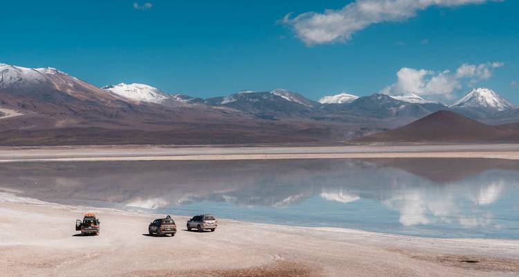 Marais salants pittoresques avec montagnes et véhicules reflétés.