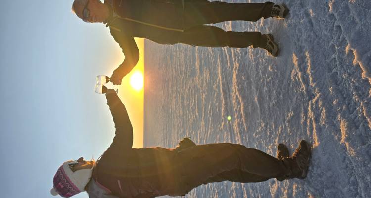 Deux personnes trinquant au coucher du soleil sur un lac salé.