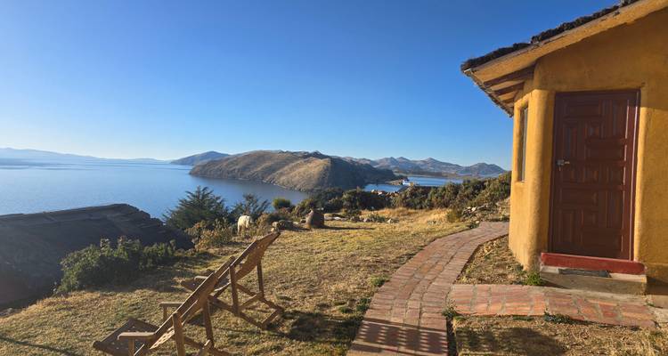 Vue sereine d'un lac et de collines avec une petite maison au premier plan.