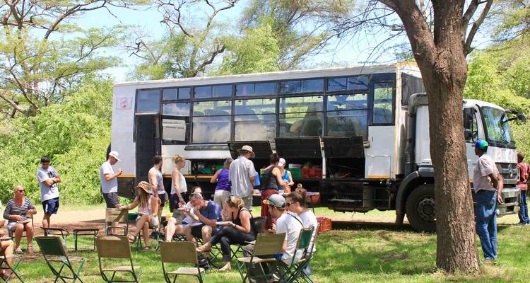 Un groupe de touristes rassemblés autour d'un grand camion de safari.
