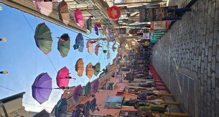 Een kleurrijke straat met paraplu's die erboven hangen en mensen die lopen.