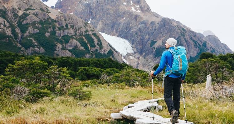 Hiker walking on a trail towards a mountain with a glacier.