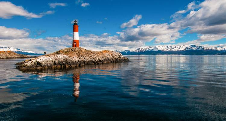 Lighthouse on a rocky outcrop surrounded by water.