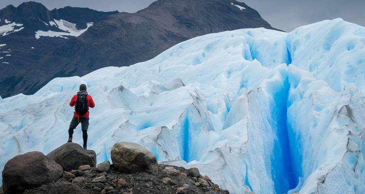 Personne debout sur des rochers regardant un glacier.