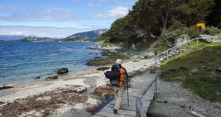 Vue arrière d'une personne marchant sur un sentier côtier avec des montagnes.