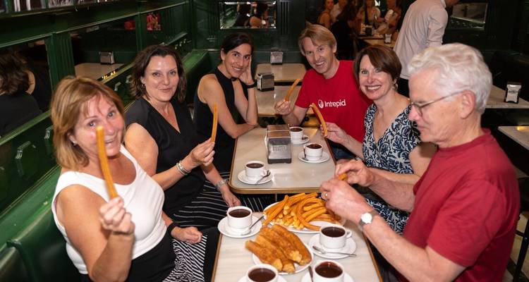Groupe de personnes savourant des churros au chocolat dans un café.
