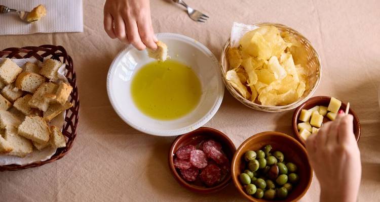 Gros plan de personnes partageant un plateau d'amuse-bouches avec du pain et des olives.