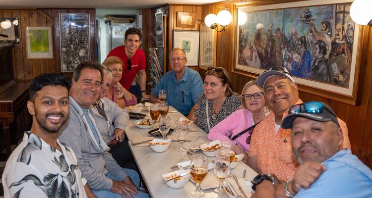 Groupe de personnes rassemblées autour d'une table, dégustant des boissons et de la nourriture.