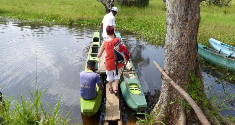 Des gens embarquant dans un petit canoë sur un lac avec un paysage verdoyant.