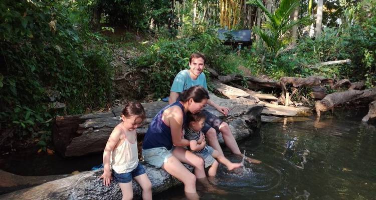Famille assise sur une bûche au bord de l'eau, profitant d'un moment ensemble.