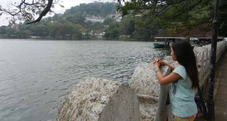 Personne regardant par-dessus un lac avec des collines and des arbres au loin.