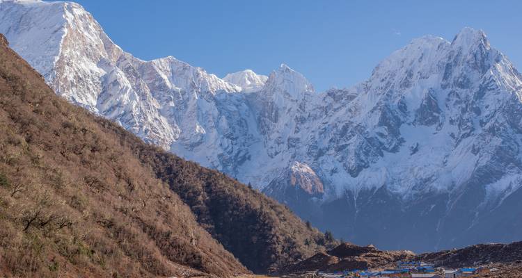 Gros plan de montagnes enneigées sous un ciel bleu dégagé.