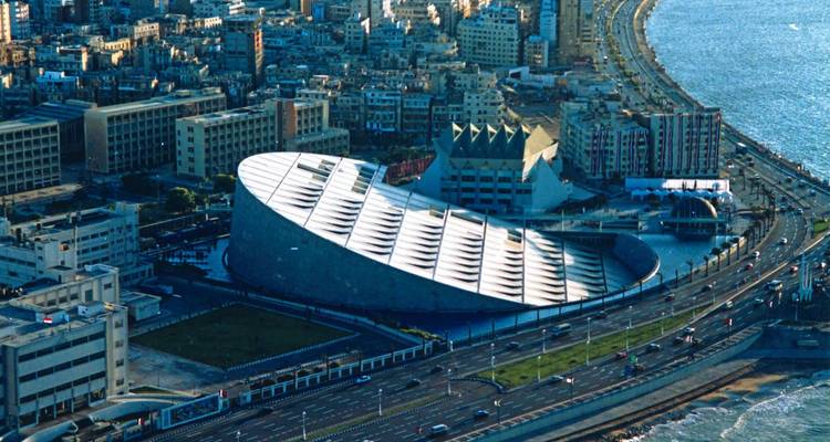 Vista aérea de la moderna Bibliotheca Alexandrina with the city and coastline in the background.