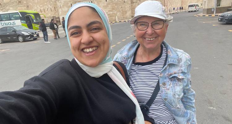 Una guía y una visitante tomándose una selfie alegre cerca de la entrada de la Ciudadela de Qaitbay.