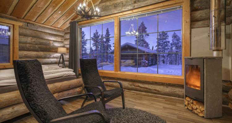 Cozy log cabin interior with a fireplace, snow visible outside.