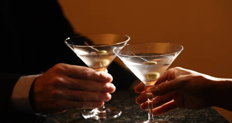 Deux mains qui trinquent avec des verres à martini.