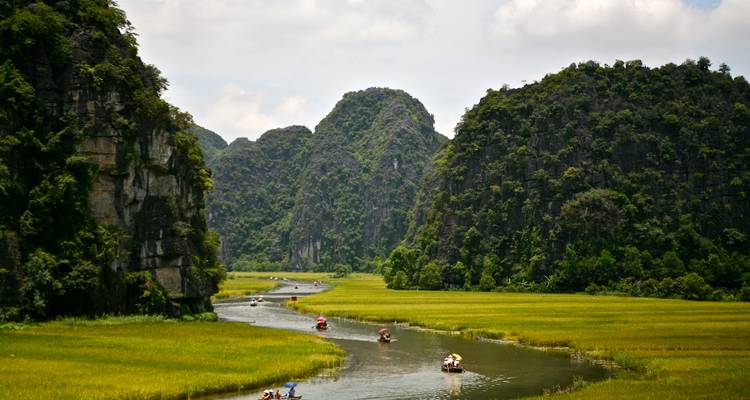 Une rivière qui coule à travers des montagnes verdoyantes luxuriantes, avec des bateaux sur l'eau.
